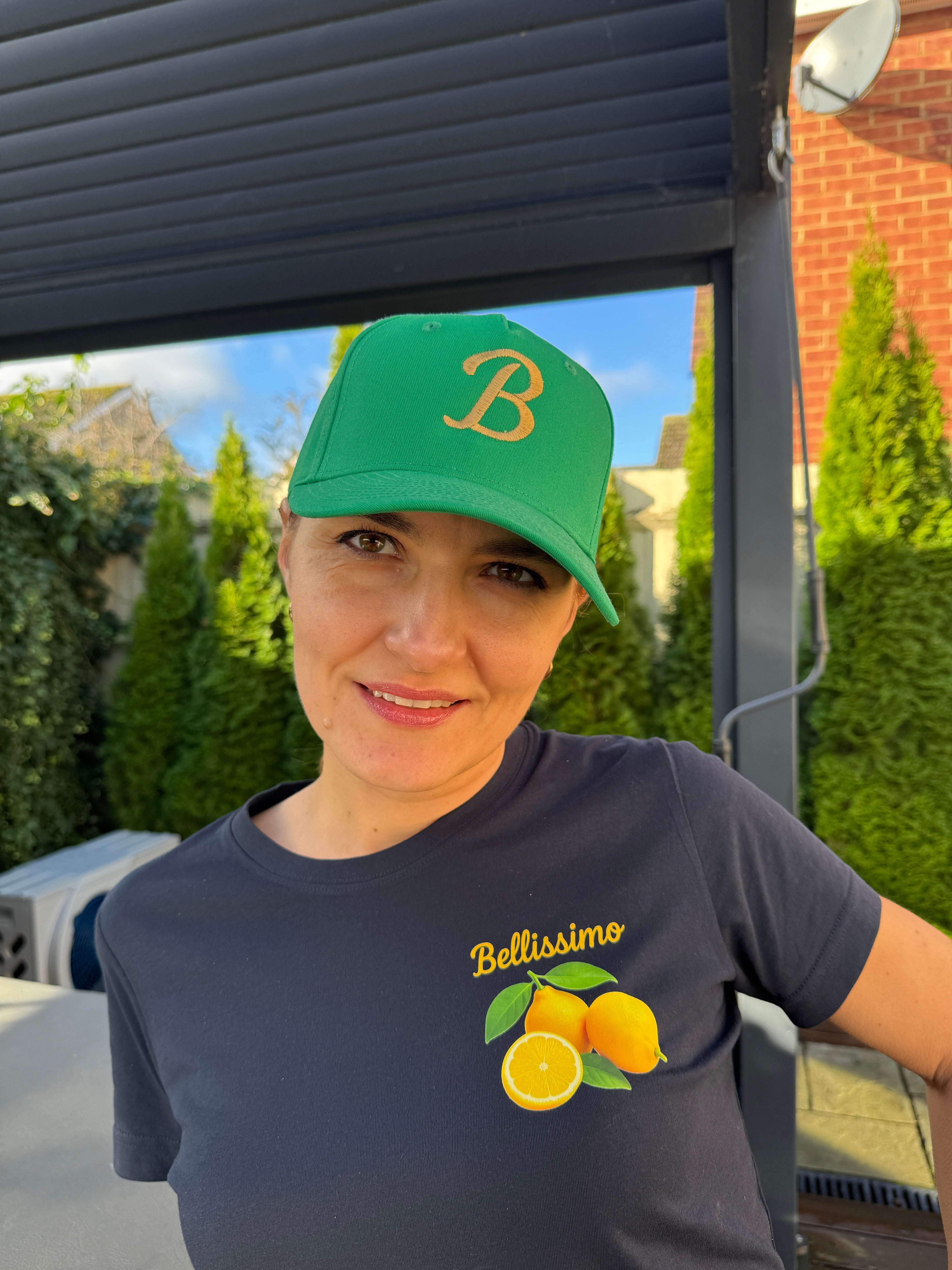 Person wearing a green cap and navy shirt with a logo, standing outdoors.